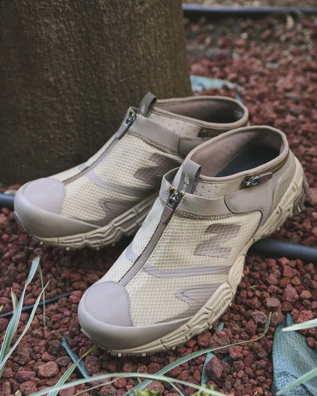 Par de New Balance Niobium Concept 1 en marrón claro en versión mule, con el cierre frontal y la puntera reforzada, sobre piedras rojas