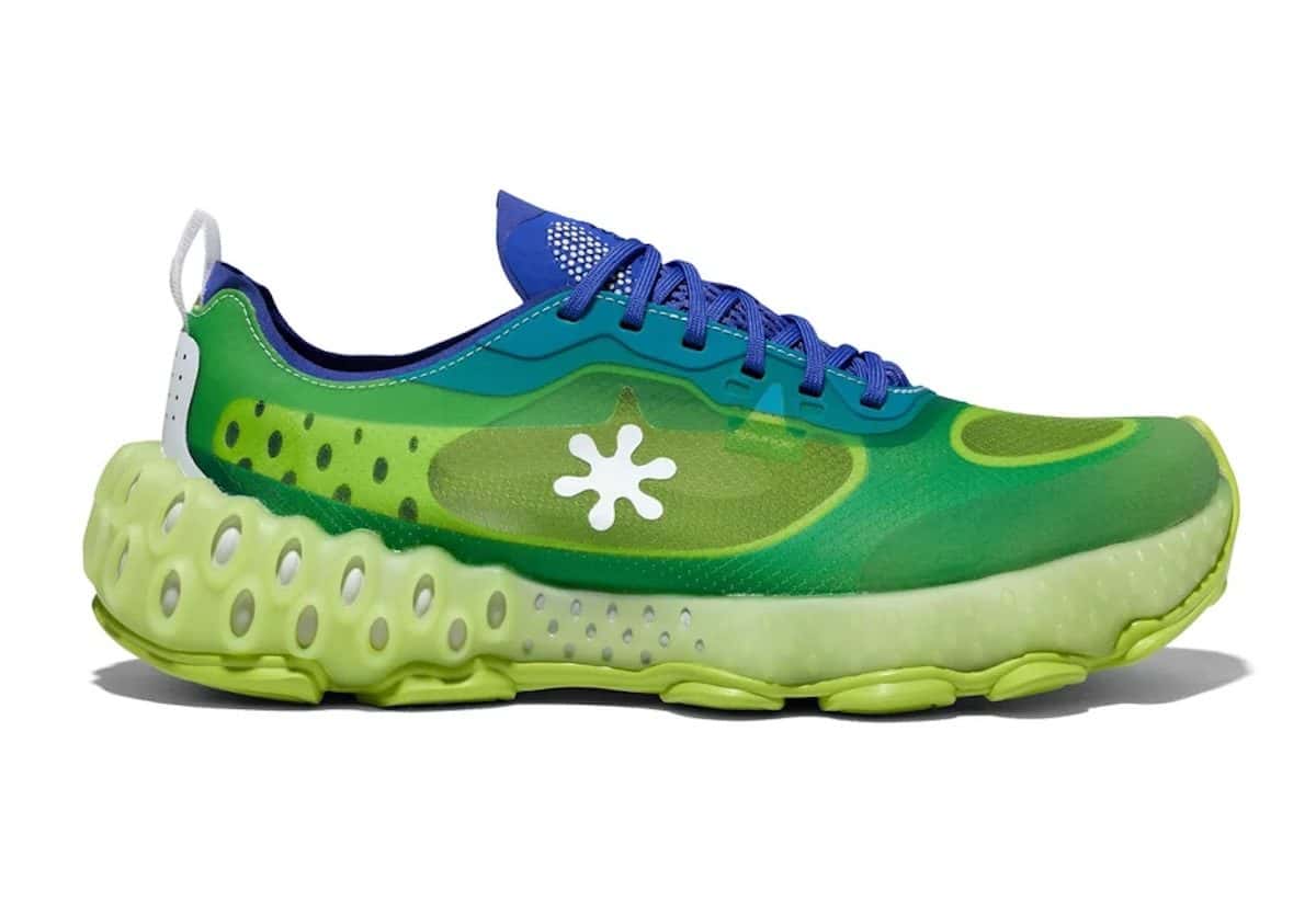 Spunge Lumina Cenote de perfil sobre fondo blanco, con capellada de malla verde translúcida, cordones azules, el logo de asterisco blanco y suela verde lima con huecos
