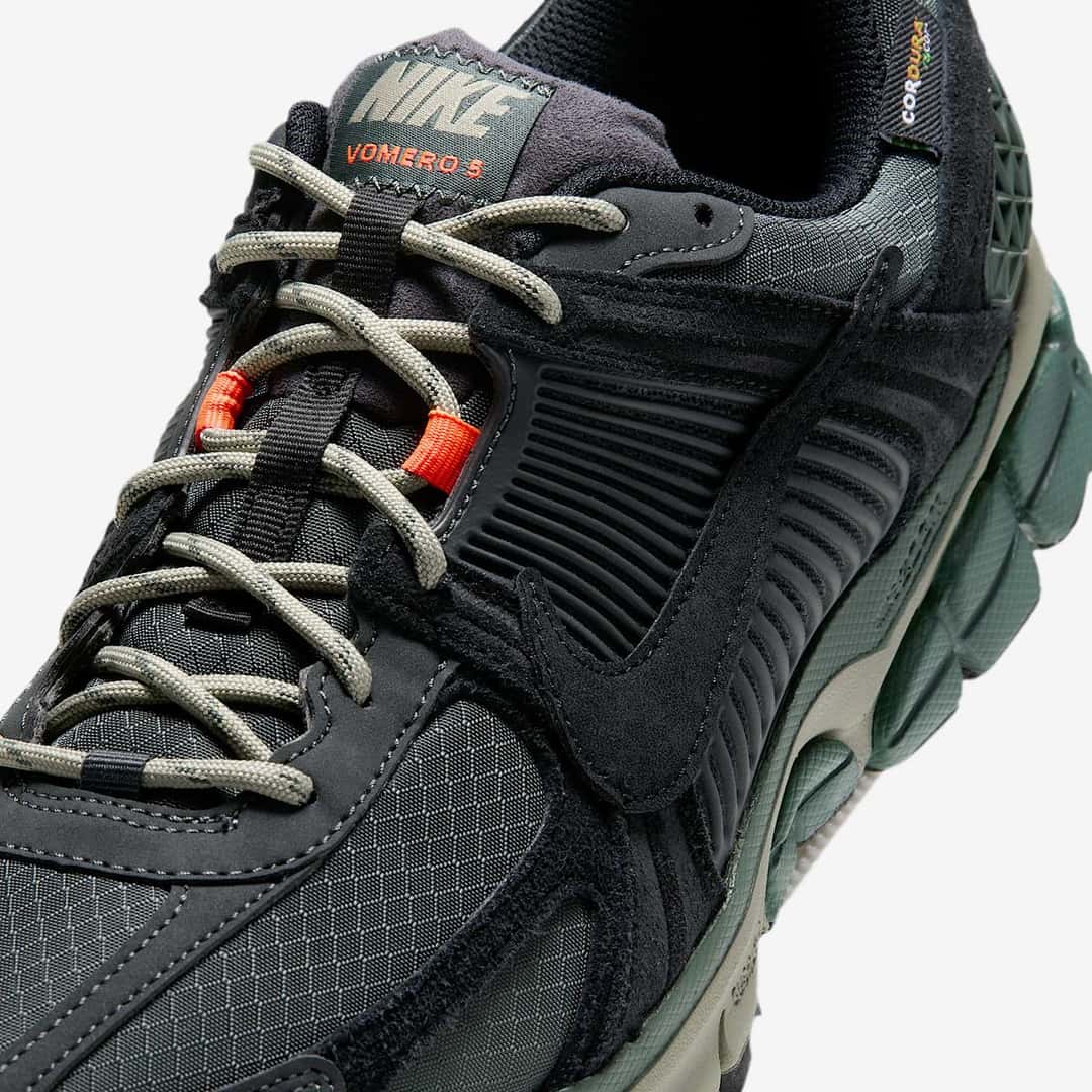 Detalle de los cordones caqui, la presilla naranja y la lengüeta de la Nike Zoom Vomero 5 Cordura Camo Green