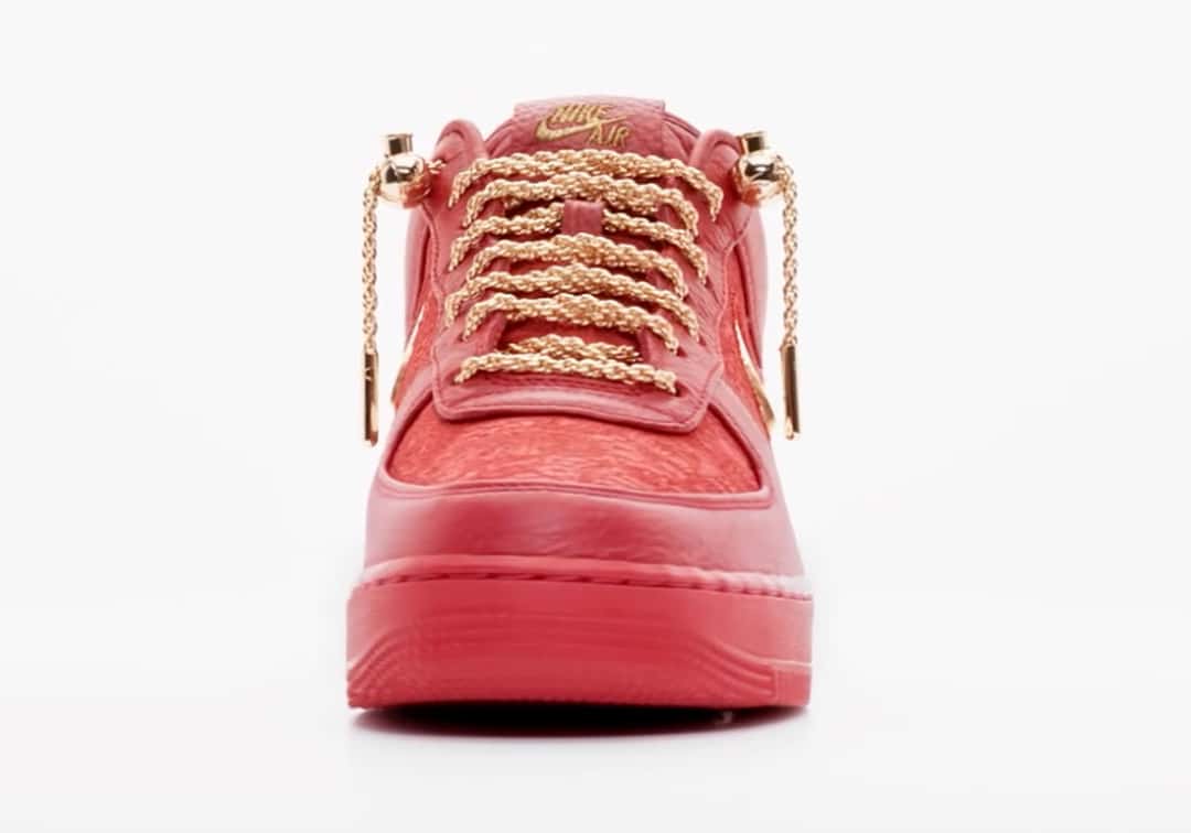 Victor Solomon x Nike Air Force 1 Low Trophies rojo de frente sobre fondo blanco, con los cordones de soga dorados, la lengüeta con el logo dorado y la puntera roja