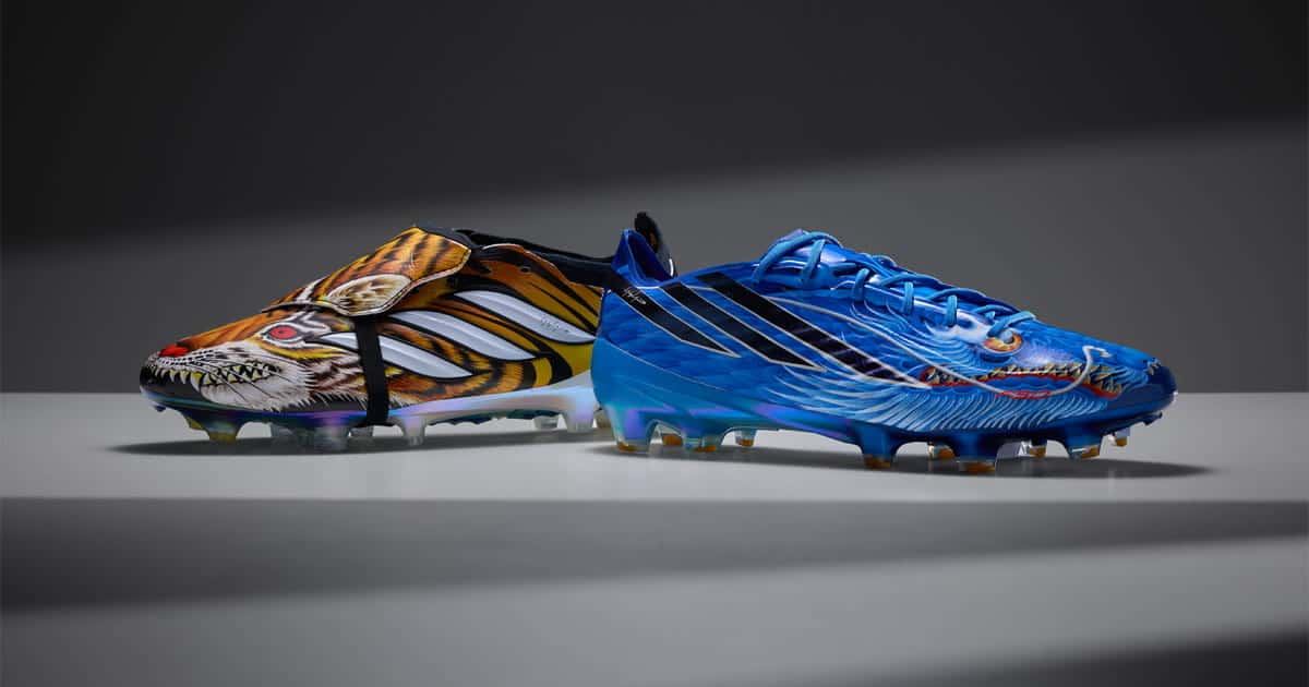 Botines adidas Predator con un tigre pintado en amarillo, naranja y negro y adidas F50 azules con un dragón, apoyados sobre una superficie gris