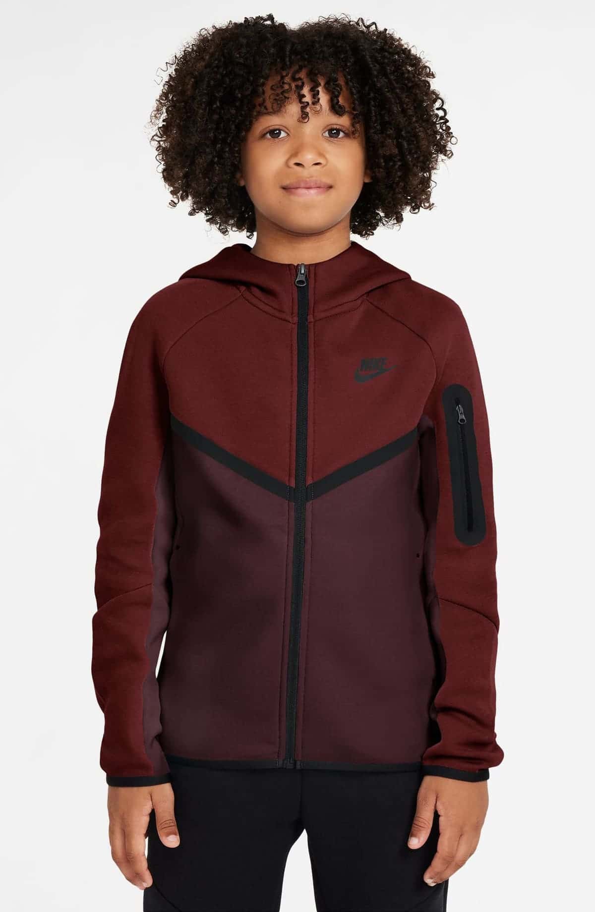 Niño con chaqueta Nike Tech Fleece con capucha en rojo y burdeos, cierre negro, chevron negro al frente y bolsillo con cierre en la manga